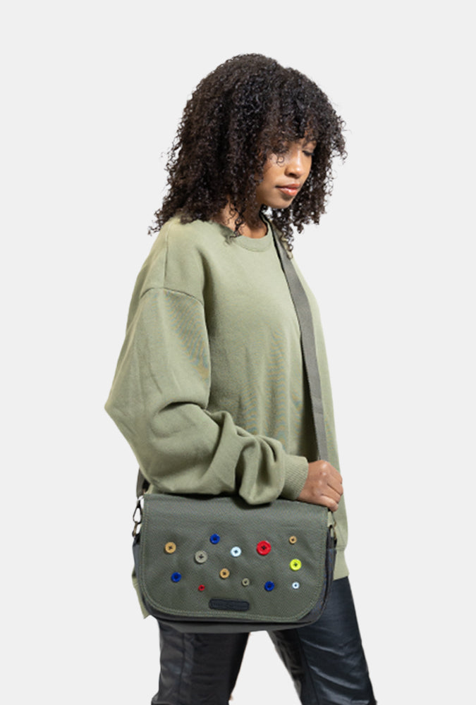 Woman holding a green Button bag with colorful buttons against a white background